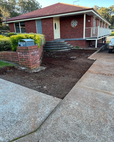 A brick retaining wall and exposed aggregate path by TJC Building