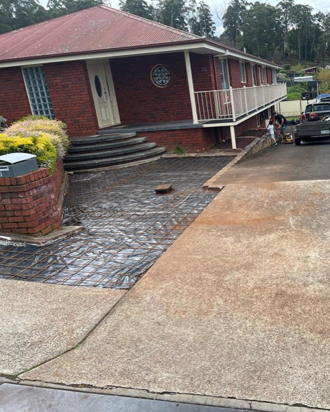 A concrete driveway poured by TJC Building beside a brick home