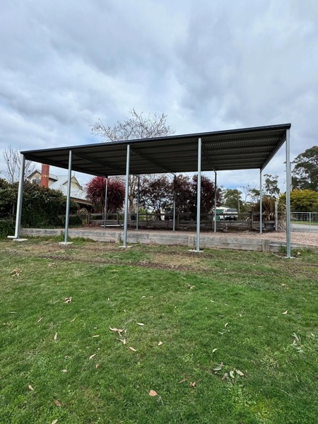 An open steel shed frame going up on a gravel base by TJC Building