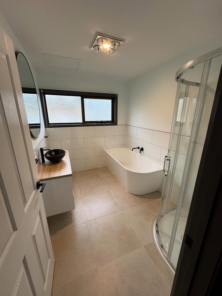 A renovated bathroom with bath and basin by TJC Building