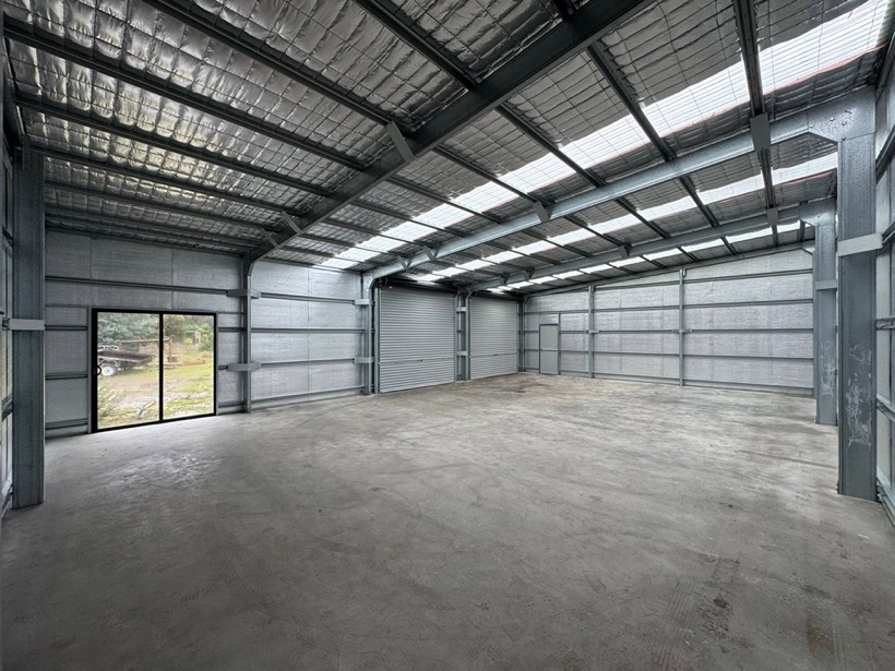 A black steel shed with a glazed sliding door by TJC Building