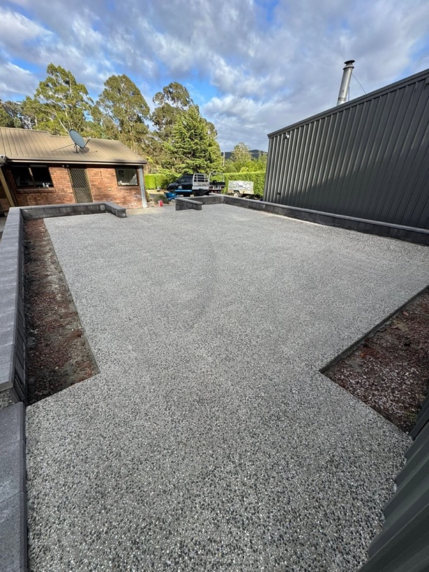 An exposed aggregate patio and steps with block retaining walls by TJC Building