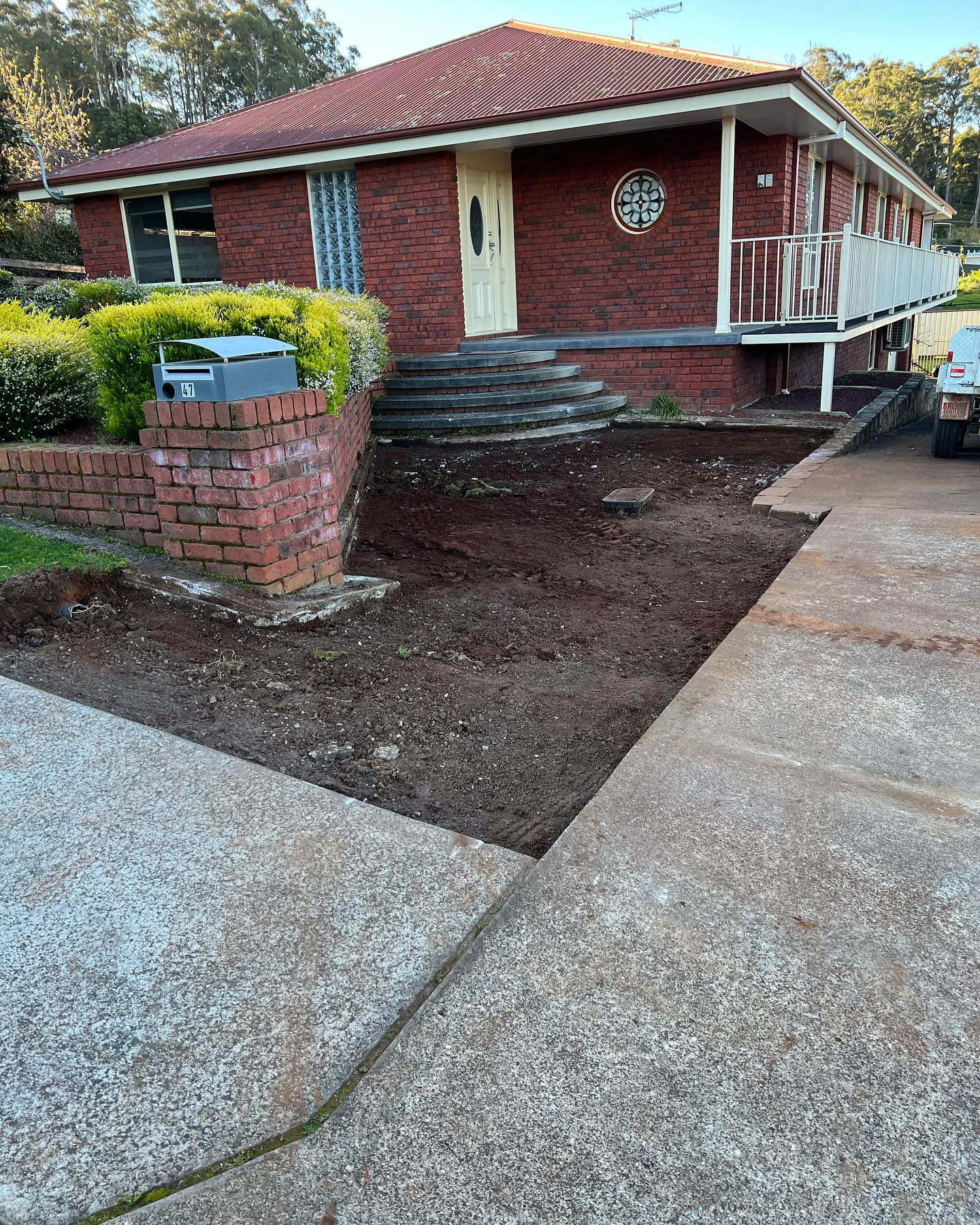 A brick retaining wall and exposed aggregate path by TJC Building